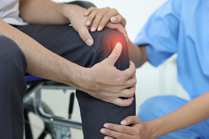 chmuckbild: eine Ärztin untersucht das schmerzende Knie eines Patienten, verlinkt zur Seite 'Praxis für Schmerztherapie'