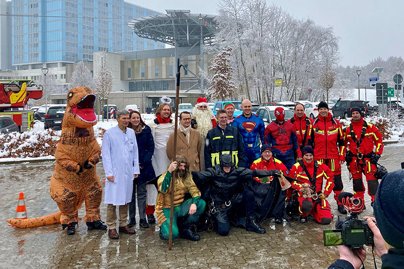 Gruppenfoto der Superhelden und Feuerwehrleute mit Dr. Renneberg, Dr. Kleinbrahm und Dr. Nickel, im Hintergrund die Hubschrauberplattform (Foto: Schimanke)