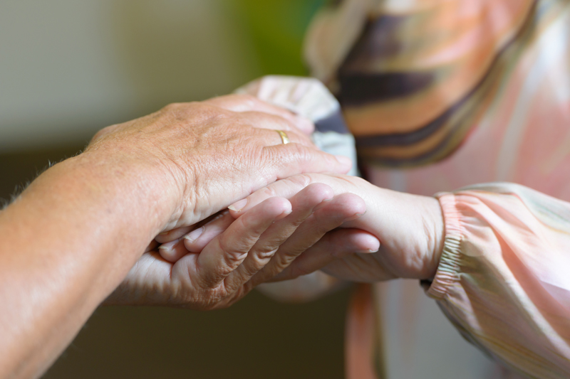 Zwei Hände einer Person umfassen zwei Hände einer anderen Person