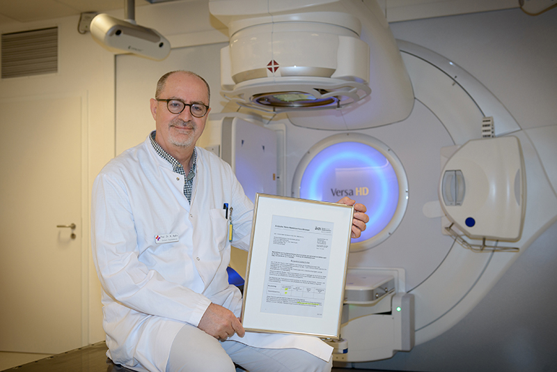 Chefarzt Professor Aydin vor dem Linearbeschleuniger mit der Urkunde aus dem Audit (Foto: Antje Schimanke) Chefarzt Professor Aydin vor dem Linearbeschleuniger mit der Urkunde aus dem Audit (Foto: Antje Schimanke)